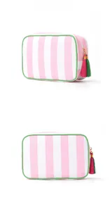 Detail view of pink and white striped makeup bag with green trim and tassel zipper pull