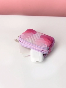 Detail of pink gradient quilted makeup pouch holding wireless earbuds and cards