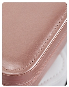 Primer plano del joyero de cuero rosa con costuras finas y textura de grano de lichi