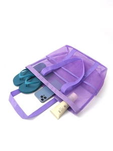 Close-up of purple mesh beach bag storing flip-flops, phone and sunscreen products