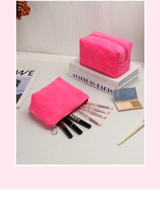 Dettaglio di pochette per trucchi in peluche rosa con cerniere su tavolo di marmo