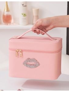 Roze make-up koffer met glanzende lippen en gouden ritsen vastgehouden in de hand in badkamer