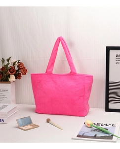 Dettaglio della borsa tote in peluche rosa neon con accessori di moda sul tavolo