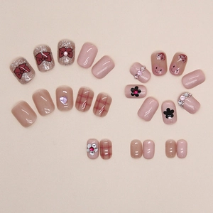 Unghie finte rosa con fiocco rosso, motivo a quadri, cuori 3D e decori floreali con strass