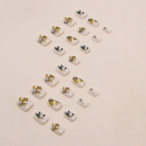 Short square press-on nails with retro hand-painted floral silhouette in cream yellow