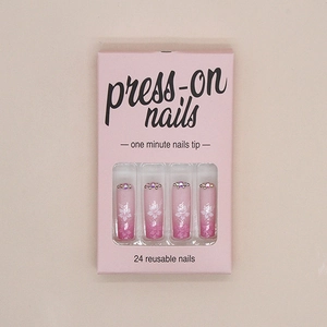 Detail of pink gradient press-on nails with white flower patterns and tiny crystal rhinestones