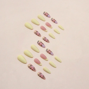 Matte yellow almond press-on nails with floral patterns and French tip design
