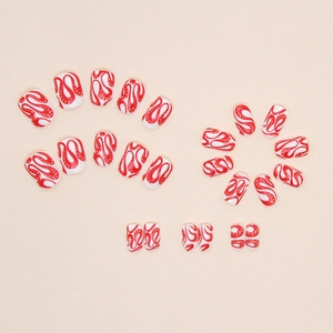 Close-up of red and white spiral pattern press-on nails set on a neutral background