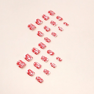 Detail of short press-on nails featuring red snake patterns and abstract swirls on white