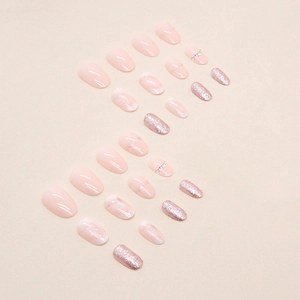 Pink marble oval press-on nails set with glitter and diamonds on a warm background