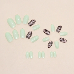 Glossy oval press-on nails in mint green and black zebra patterns on beige background