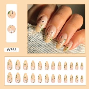 Almond shaped press-on nails with nude gradient base and delicate white floral patterns