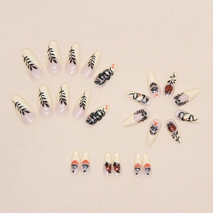 Détail de faux ongles amande noirs avec motifs de rose, serpent et œil mystique