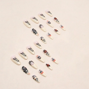 Vue détaillée de motifs de serpent noir et de rose sur des faux ongles de forme amande