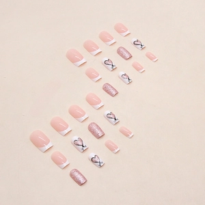 Unghie finte French rosa e bianche con dettagli glitterati e motivi a cuore