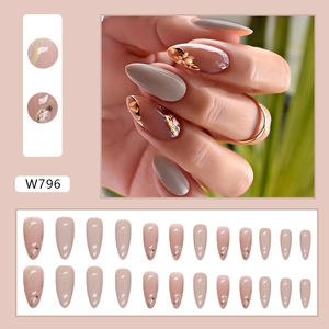 Macro detail of almond-shaped press-on nails with floral art and golden accents