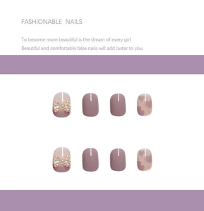 Detail of purple press-on nails featuring 3D bows, solid tones, and heart patterns
