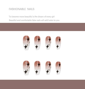 Detail of reddish-brown gradient press-on nails with black cross stars and tiny rhinestones
