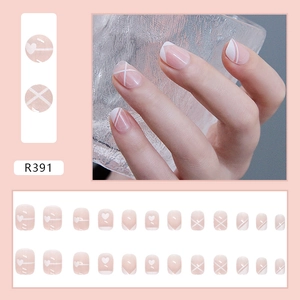 Detail view of pink R391 press-on nail set featuring white hearts and geometric French lines