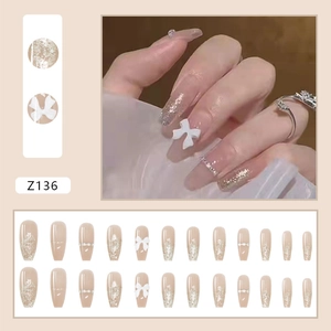 Details von nude-rosa Klebenägeln mit silbernem Glitzer und weißen 3D-Schleifen-Charms