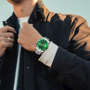 Detail of green diver watch with stainless steel strap and luminous rotating bezel