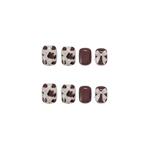 Faux ongles léopard marron avec tons rouges et décorations de nœuds blancs en 3D