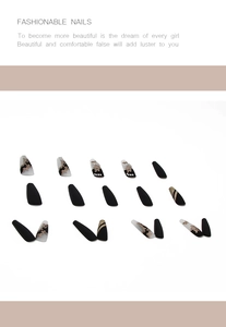 Detail of long stiletto press-on nails with matte black, floral art, and gold glitter stripes