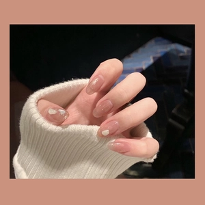 Close-up of nude gradient press-on nails with gold glitter and shell flakes on hand