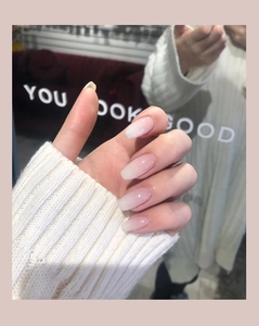 Detailed view of pink to white ombre ballet shape press-on nails with YOU LOOK GOOD text