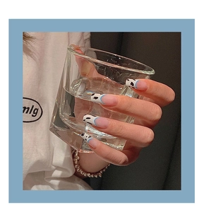 Gros plan de longs faux ongles ballerine avec pointes bleues et motif vache