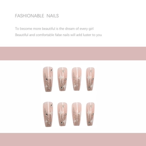 Close-up of ombre pink press-on nails with white star patterns and small silver rhinestones