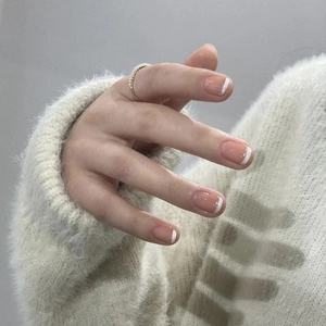 French tip press-on nails in pink and white, shown on hand with a gold pearl ring