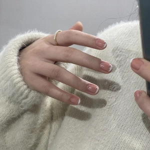 French tip press-on nails in nude pink with a minimalist golden ring on model's hand