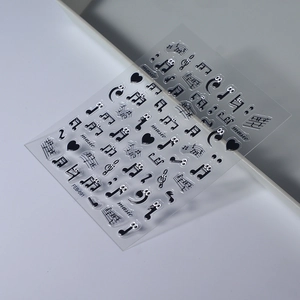 Macro view of music themed nail stickers with black notes and cartoon eye heart patterns
