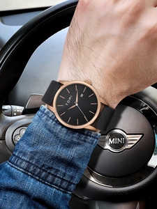 Close-up of a minimalist TOMI watch with black dial and leather strap worn while driving