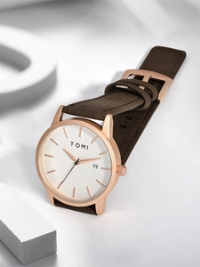 Detail of rose gold quartz watch with brown suede strap and date display on white dial