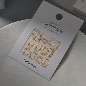 Close-up of gold embossed nail art stickers with crystal rhinestones on marble surface