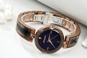 Macro detail of starry blue dial and rose gold band with sparkling crystal marker
