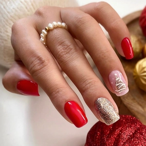 Macro detail of red and gold Christmas press on nails with 3D white embossed tree art