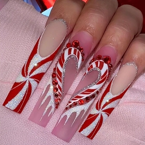 Detailed view of long square Christmas press-on nails with candy stripes and red rhinestones