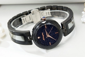 Close-up of starry sky dial and faceted bezel with black segmented steel watch strap