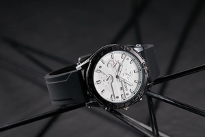 Macro shot of white chronograph watch dial with black bezel and date window on a sleek stand