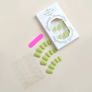 Flat lay of green tortoise press-on nails set with nail file and adhesive tabs