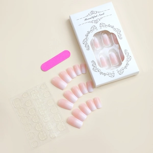 Pink gradient press-on nails set with packaging, adhesive tabs, and manicure tool kit