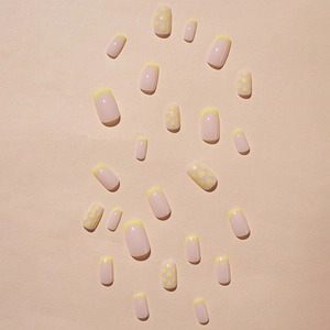 French tip press-on nails with yellow heart designs on a nude pink base, full kit