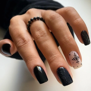 Close-up of black snowflake press on nails with glitter finish and beaded ring detail