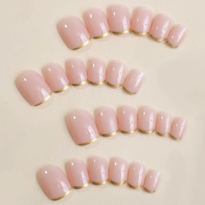 Short square press-on nails with translucent jelly pink base and metallic gold French tips