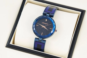 Close-up of women's starry sky watch with faceted glass and blue steel strap in a box