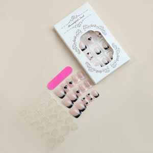 Detail view of Valentine press on nails kit with black heart patterns and nail file