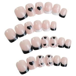 Press-on nail set in nude pink with heart patterns and black french tips on white base